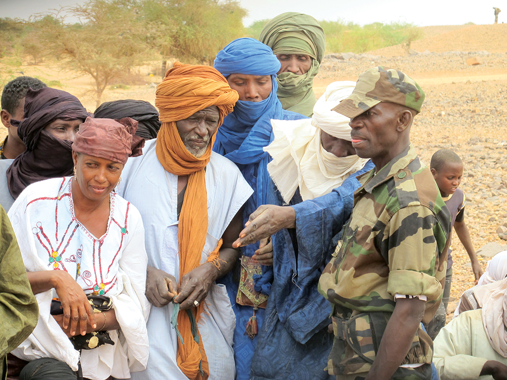 Un soldat nigérien (à droite) s’entretient avec des villageois faisant la queue pour obtenir une aide médicale au service de consultations externes, à Gofat. [PERSONNEL D’ADF]