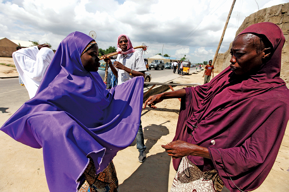 Habiba Saadu, right, of the Civilian Joint Task Force, searches a woman at a checkpoint in Maiduguri, Nigeria. Saadu said she has lost her entire family to Boko Haram and the unrest it has caused in the area. [THE ASSOCIATED PRESS]