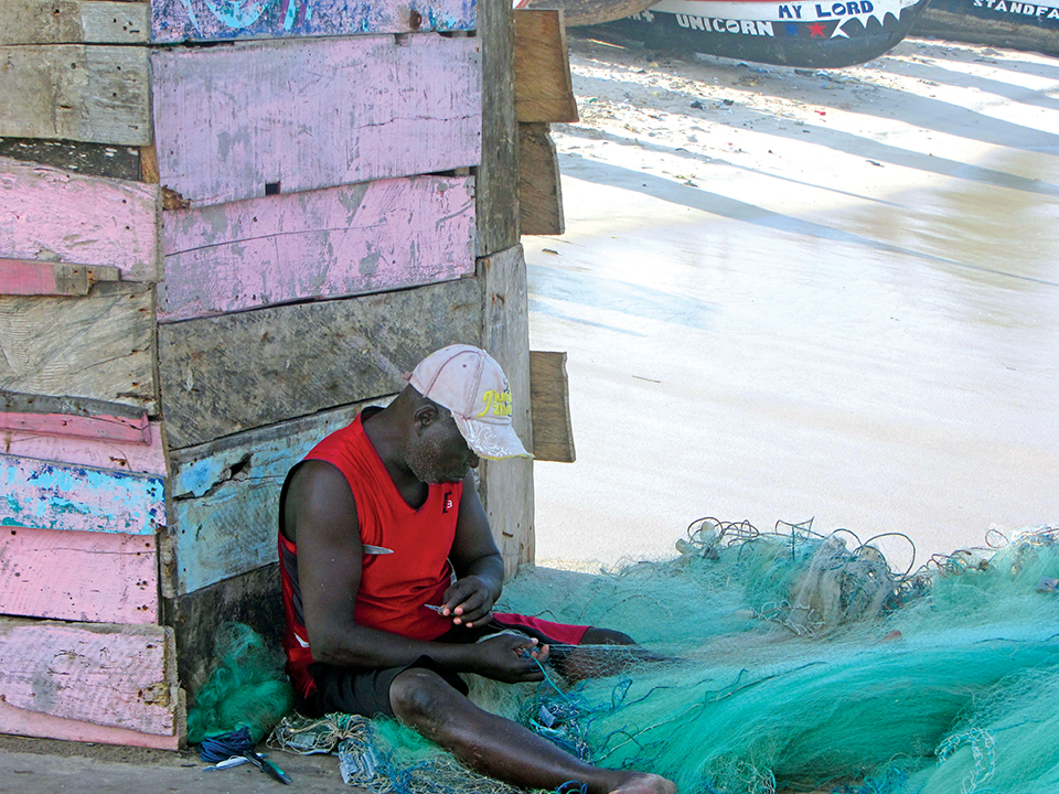 Un homme répare des filets de pêche à Accra, au Ghana. Les marins ghanéens et les sociétés de sécurité privée travaillent côte à côte pour sécuriser les intérêts pétroliers et engager une action de proximité auprès des communautés locales de pêcheurs. [ADF STAFF]