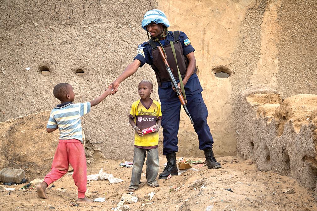 Un soldat de la paix rwandais serre la main d’un enfant lors d’une patrouille à Gao, au Mali, dans le cadre de la Mission multidimensionnelle intégrée des Nations Unies pour la stabilisation au Mali. [MINUSMA]