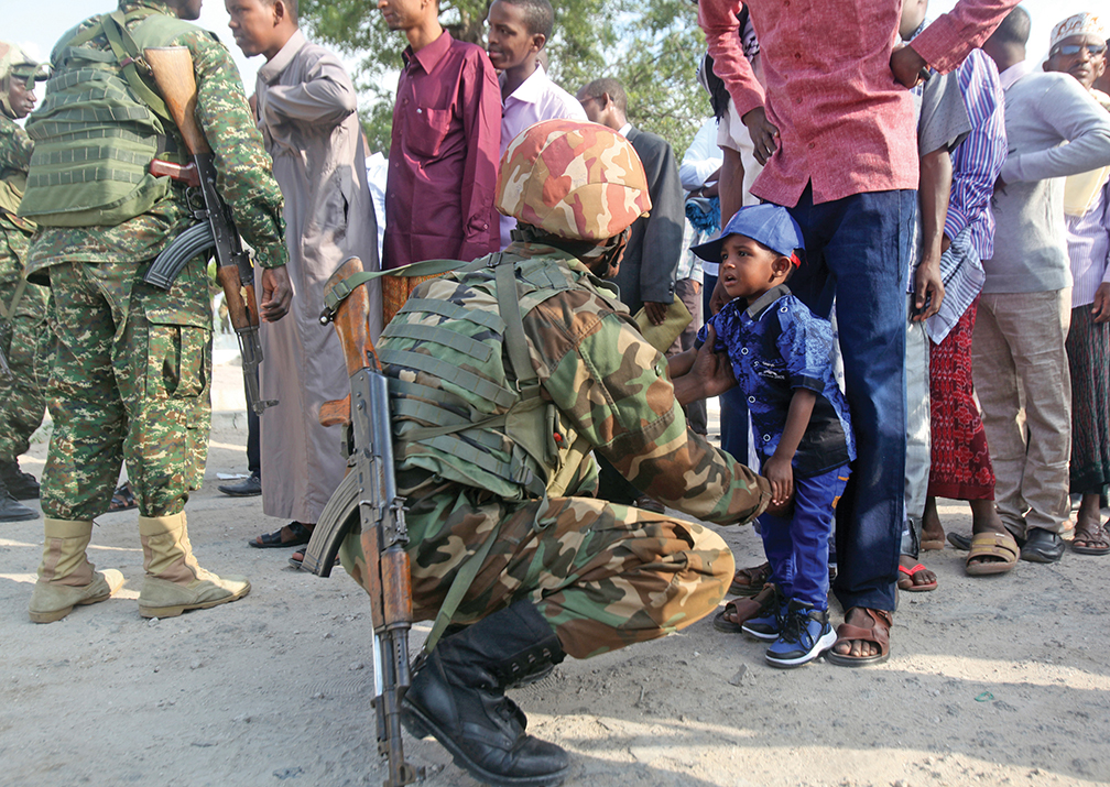 A Soldier serving in the African Union Mission in Somalia talks to a small boy at the entrance to a mosque. Military codes of conduct spell out how Soldiers are to show respect to civilians in conflict areas. REUTERS