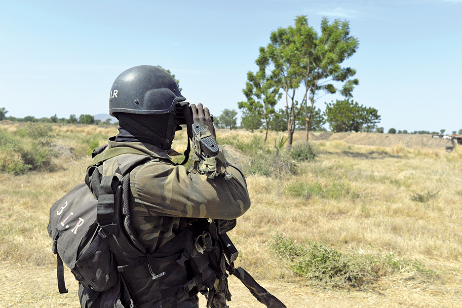 A Cameroonian soldier looks at the border through binoculars on November 12, 2014 in Amchide, northern Cameroon, 1 km from Nigeria. The city was raided by Islamists from Nigeria's Boko Haram, killing eight cameroonian soldiers and leading the population to flee on October 15, 2014, before another six coordinated attacks that killed at least three civilians in the remote north of the country, on November 9, 2014. Boko Haram's five-year insurgency in neighboring Nigeria has left thousands dead, and the Islamists have occasionally carried out attacks over the border. Cameroon has deployed more than 1,000 soldiers in the extreme northeast of the country to counter the Islamist threat. AFP PHOTO/REINNIER KAZE        (Photo credit should read Reinnier KAZE/AFP/Getty Images)