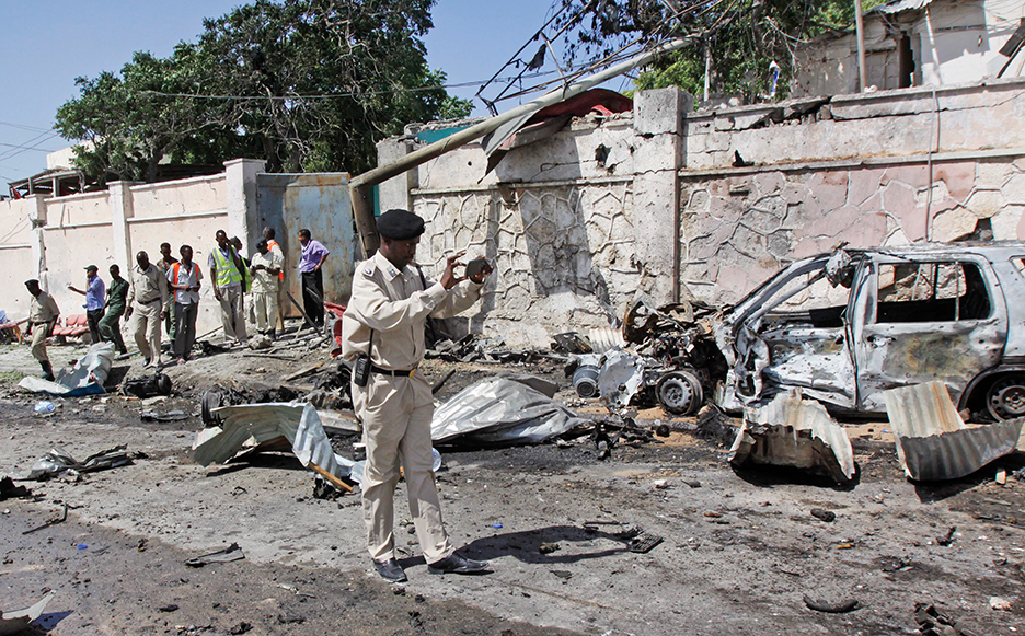 A Somali soldier takes pictures using his smartphone next to wreckage at the scene of a suicide car bomb attack that targeted a United Nations convoy, outside the airport in Mogadishu, Somalia Wednesday, Dec. 3, 2014. A Somali police officer says a suicide bomber rammed his vehicle into a U.N. convoy near Mogadishu's airport, killing three people. (AP Photo/Farah Abdi Warsameh)