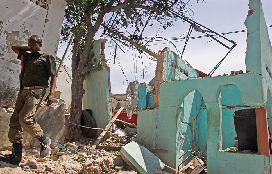 A Somali soldier walks past a nearby building destroyed by a suicide car bomb attack that targeted a United Nations convoy, outside the airport in Mogadishu, Somalia Wednesday, Dec. 3, 2014. A Somali police officer says a suicide bomber rammed his vehicle into a U.N. convoy near Mogadishu's airport, killing three people. (AP Photo/Farah Abdi Warsameh)