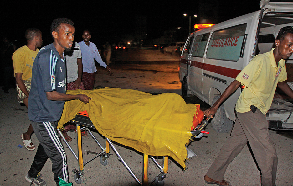 Rescuers remove a dead body from the scene of a car bomb attack close to the presidential palace in the capital Mogadishu, Somalia, Wednesday, Oct. 15, 2014.  The car bomb detonated while a group of children were walking by, killing at least five people and wounding others, a Somali police official said. (AP Photo/Farah Abdi Warsameh)