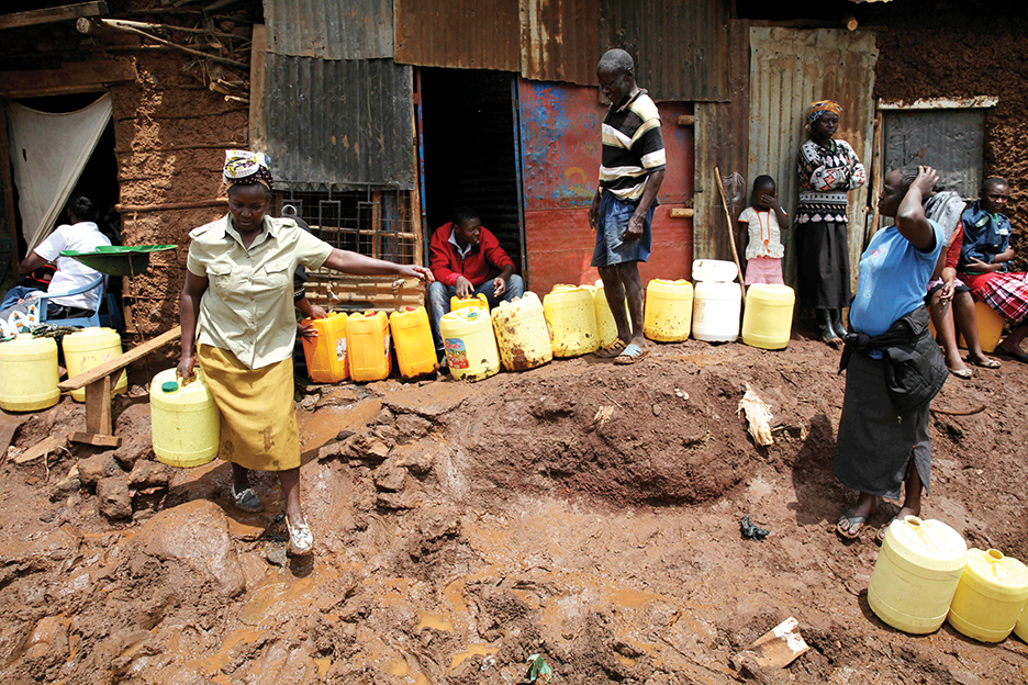 A Kenyan woman carries water after queuing for hours to reach the water tap in Nairobi's Kibera slum November 13, 2014. Rising before dawn, the women emerged from their ramshackle shacks and squelched through the mud to stand in line for water in Kibera, Nairobi's biggest slum. Picture taken November 13, 2014. To match Feature WOMEN-CITIES-KENYA/WATER   REUTERS/Thomson Reuters Foundation/Katy Migiro (KENYA - Tags: SOCIETY) - RTR4FNQE