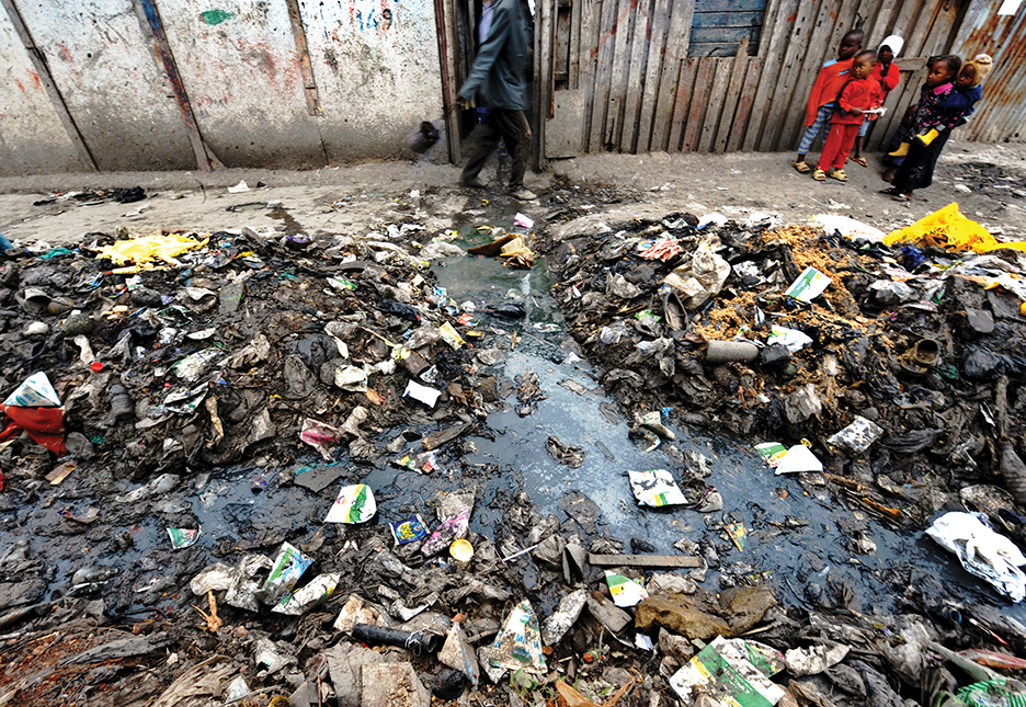 Slum residents walk past stagnated waste water and strewn rubbish in Nairobi's Mukuru -kwa-Njenga slum on July 6, 2010 where security, especially for women, is virtually non-existent as they suffer routine attacks from sexual predators in the slum especially as they commute to the communal bathrooms within the slum. Women and girls in Nairobi's slums live under the constant threat of sexual violence, leaving them often too scared to leave their houses to use communal toilet and bathroom facilities, Amnesty International has said in a report released today. Titled, 'Insecurity and Indignity: Women's experiences in the slums of Nairobi, Kenya' the report details how the failure of the government to incorporate the slums in urban plans and budgets has resulted in poor access to services like sanitation, which hits women in slums and informal settlements especially hard.    AFP PHOTO/ TONY KARUMBA (Photo credit should read TONY KARUMBA/AFP/Getty Images)